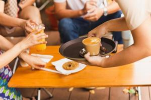 serveerster portie heet latte koffie naar klant Bij cafe. foto