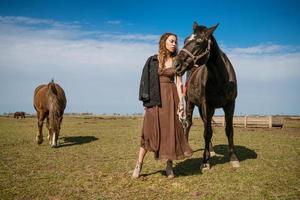 mooi jong vrouw in een veld- met paarden. aantrekkelijk mode model. foto