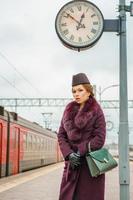 mooi modieus vrouw Aan de platform aan het wachten, somber herfst dag foto