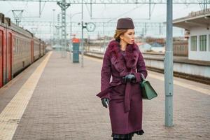 mooi modieus vrouw Aan de platform aan het wachten, somber herfst dag foto