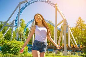 gelukkig glimlach meisje staat in een amusement park Aan een zonnig dag. modieus portret . foto