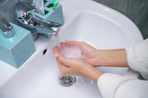 vrouw wast haar hand- in de badkamer wasbak, zonder een gezicht foto