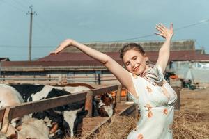 een mooi vrouw Aan een boerderij feeds de vee met hooi foto