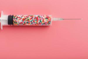 injectiespuit gevulde met kleurrijk nano ballen Aan een roze achtergrond. foto