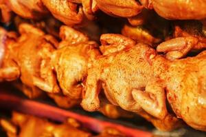sappig en smaakvol gegrild kip met een gouden korst Aan een vleespen in een rij. foto
