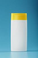 wit plastic fles met geel pet met shampoo gel Aan blauw achtergrond. foto