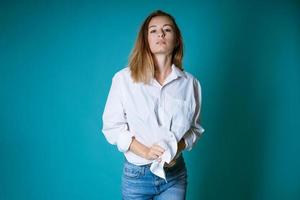 jong vrouw poseren in wit overhemd en jeans Aan blauw achtergrond foto