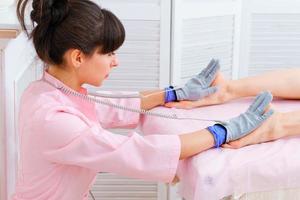masseuse maakt een Anti-cellulitis massage Aan poten. microsensorisch elektrisch foto
