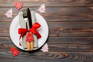 top visie van bord, vork en mes geserveerd Aan Kerstmis versierd houten achtergrond. nieuw jaar vooravond concept met kopiëren ruimte foto