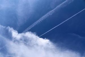 condensatiesporen van vliegtuigen in de blauwe lucht tussen enkele wolken foto