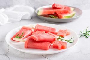 watermeloen ijslolly en stukken van watermeloen Aan een bord Aan de tafel. eigengemaakt toetje foto