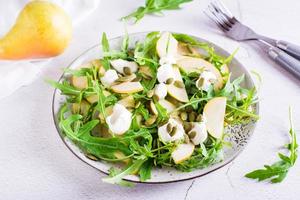 vers salade met peren, rucola, Ricotta en pompoen zaden Aan een bord Aan de tafel. eigengemaakt lunch foto