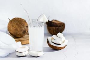 kokosnoot melk in een glas met een rietje en stukken van tropisch fruit Aan de tafel. foto
