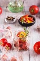 eigengemaakt zon gedroogd tomaten met kruiden, knoflook en kruiden in een pot en vers groenten. verticaal foto