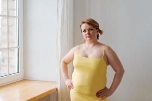 portret vrolijk aantrekkelijk jong mollig plus grootte vrouw in geel strak jurk foto