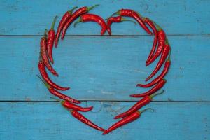 hart vormig heet Chili peper gelegd uit Aan een blauw houten achtergrond foto