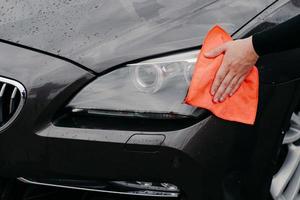 mans hand afvegen auto koplamp met microfiber doek. auto detaillering. onderhouds- en transportconcept foto