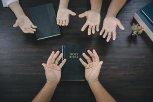 een groep van Aziatisch christenen zit binnen een Katholiek kerk bidden voor godzijdank zegening, de pale zon schijnend in de plaats van aanbidding. foto