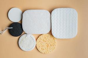 assortiment van gelaats sponzen Aan een beige achtergrond. ronde en plein gelaats sponzen gemaakt van natuurlijk ecologisch materialen voor hygiënisch zelf zorg foto