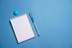 notitieboekje en pen Aan een blauw achtergrond. top visie met kopiëren ruimte. schrijfbehoeften foto