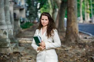 de portret van een bedrijf vrouw met een notitieboekje in haar hand. slim gekleed meisje buiten. geslaagd wit Europese vrouw foto