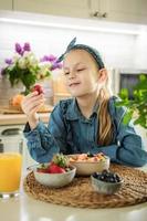 schattig klein meisje eet fruitsalade foto