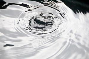 water druppels of water kralen vallen Aan de water oppervlakte veroorzaken de water oppervlakte naar verspreiden en schuim. foto