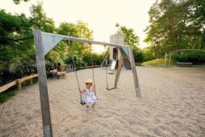 baby meisje schommel in kinderen speelplaats speelgoed- reeks in openbaar park. foto