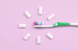 tandenborstel en kauwen tandvlees liggen Aan een pastel roze achtergrond foto