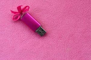 briljant roze USB flash geheugen kaart met een roze boog leugens Aan een deken van zacht en harig licht roze fleece kleding stof. klassiek vrouw geschenk ontwerp voor een geheugen kaart foto