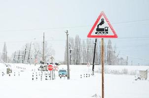 spoorweg kruispunt zonder een barrière met een veel van waarschuwing tekens in de besneeuwd winter seizoen foto