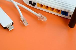 internet router, portable USB Wifi adapter en internet kabel pluggen liggen Aan een helder oranje achtergrond. items verplicht voor internet verbinding foto