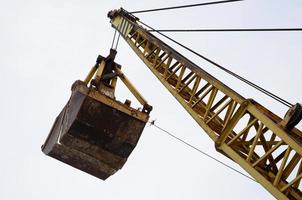 oud geel mechanisch clamshell grijp Aan blauw lucht achtergrond foto