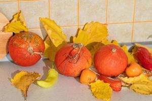 seizoensgebonden oogst van pompoenen en groenten, ingrediënten voor voorbereidingen treffen een gerecht, reclame en herfst concept - detailopname van pompoenen en bladeren Aan de tafel Bij huis foto