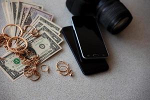 veel duur gouden jewerly ringen, oorbellen en kettingen met groot bedrag van ons dollar rekeningen dichtbij naar smartphones en digitaal slr camera. pion winkel foto