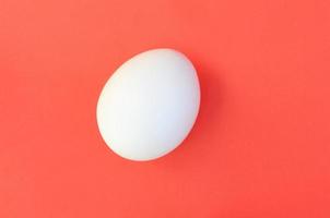 een wit ei Aan een helder rood achtergrond foto