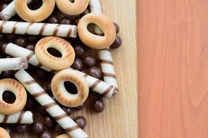 krokant buisjes, chocola smelten ballen en bagels liggen Aan een houten oppervlak. mengen van divers snoepgoed foto