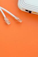 internet router en internet kabel pluggen liggen Aan een helder oranje achtergrond. items verplicht voor internet verbinding foto