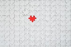 de structuur van een wit decoupeerzaag puzzel in een gemonteerd staat met een missend element vormen een rood ruimte foto
