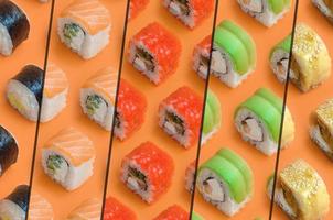 collage met verschillend types van Aziatisch sushi broodjes Aan oranje achtergrond. minimalisme top visie vlak leggen patroon met Japans voedsel foto