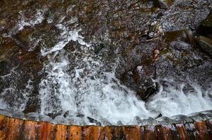 handgemaakt houten water afvoeren van klein behandeld balken. een mooi fragment van een klein waterval foto