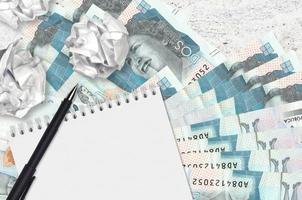 2 Colombiaanse pesos rekeningen en ballen van verfrommeld papier met blanco kladblok. slecht ideeën of minder van inspiratie concept. zoeken ideeën voor investering foto