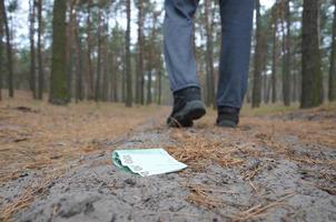 jong Mens verliest zijn euro geld rekeningen Aan Russisch herfst Spar hout pad. onzorgvuldigheid en verliezende geld concept foto