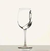 een plons van wit wijn in een glas voor wijn. water spatten. drinken water. alcohol. geïsoleerd Aan wit achtergrond foto