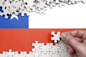 Chili vlag is afgebeeld Aan een tafel Aan welke de menselijk hand- vouwen een puzzel van wit kleur foto