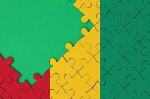 Guinea vlag is afgebeeld Aan een voltooid decoupeerzaag puzzel met vrij groen kopiëren ruimte Aan de links kant foto