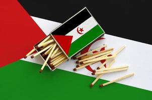 western Sahara vlag is getoond Aan een Open luciferdoosje, van welke meerdere wedstrijden vallen en leugens Aan een groot vlag foto