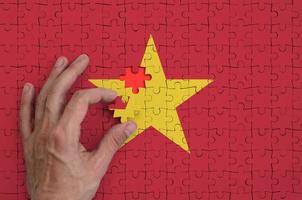 Vietnam vlag is afgebeeld Aan een puzzel, welke de man's hand- voltooit naar vouwen foto