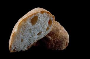 ciabatta, een brood van brood besnoeiing in voor de helft geïsoleerd Aan een zwart achtergrond. foto