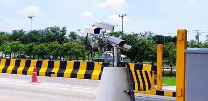 groep van cctv camera geïnstalleerd voor opname ongeluk Aan weg of straat met geschilderd geel en zwart barrière, . boom en lucht achtergrond. bescherming, observeren verkeer en houden vervoer. foto